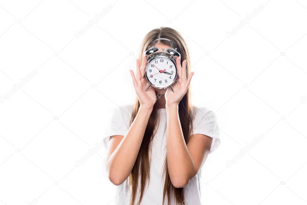 Girl covering face with alarm clock