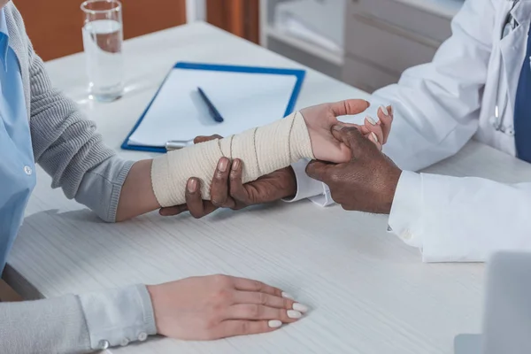 Läkaren undersöker skadade handen — Stockfoto