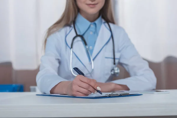 Doctor writing something on clipboard — Stock Photo, Image