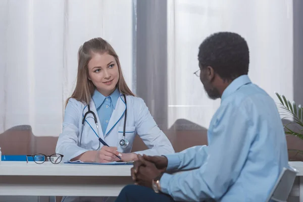 Лікар сидить і слухає пацієнта — стокове фото