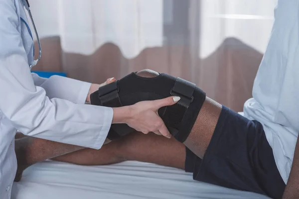 Doctor putting on knee brace — Stock Photo, Image