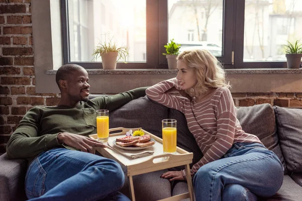 Retrato Multicultural Jovem Casal Sentado Sofá Enquanto Tomando Café Manhã — Fotografia de Stock