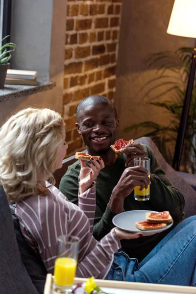 家で一緒に朝食を食べて陽気な多文化の若いカップル  — 無料ストックフォト