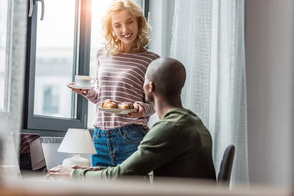 Fidanzata Portato Una Tazza Caffè Croissant Fidanzato Afroamericano Che Lavora — Foto stock gratuita