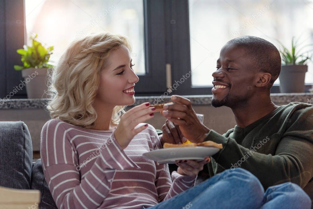 portrait of happy multicultural young couple having breakfast together at home
