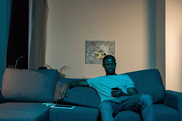 african american man with smartphone at home