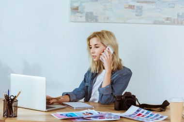 portre Studio işyerinde o dizüstü bilgisayar çalışırken Smartphone'da konuşuyor odaklı fotoğrafçı