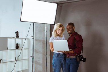 Afrika kökenli Amerikalı fotoğrafçı ve beyaz model laptop photoshoot sırasında birlikte fotoğraf stüdyosunda seçme