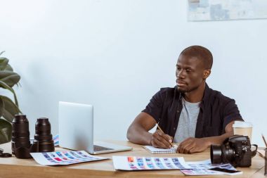 ofiste dizüstü bilgisayar ile işyerinde çalışmaya konsantre Afrikalı-Amerikalı fotoğrafçı portresi
