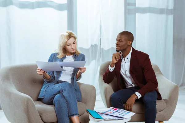 Fotógrafos Interracial Elegir Fotos Juntos Mientras Están Sentados Sillones Oficina — Foto de stock gratis