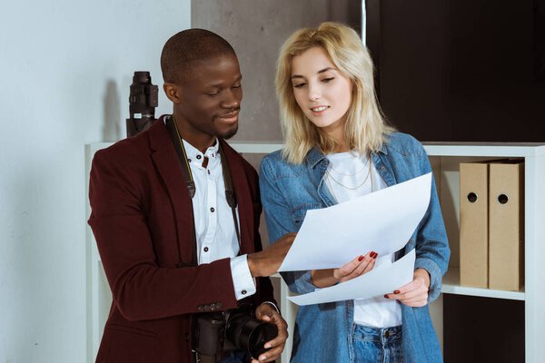 portrait of multiethnic photographers looking at portfolio together in studio