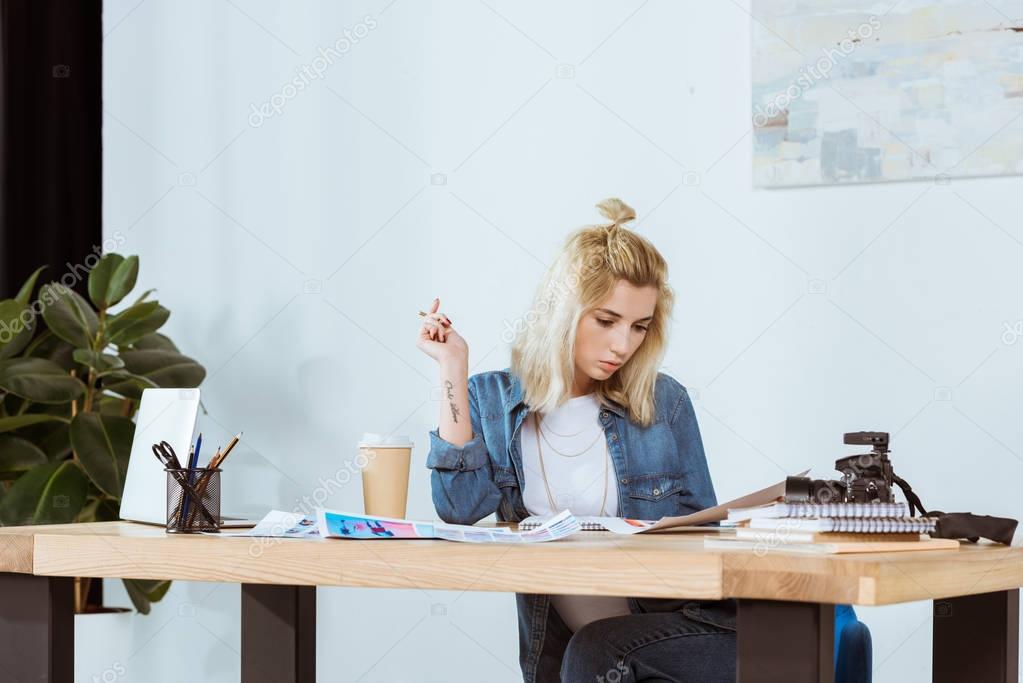 portrait of thoughtful photographer looking at photoshoot examples at workplace in office