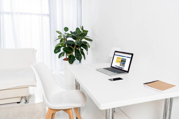 home office with laptop with bookingcom logo, smartphone and notebook on table