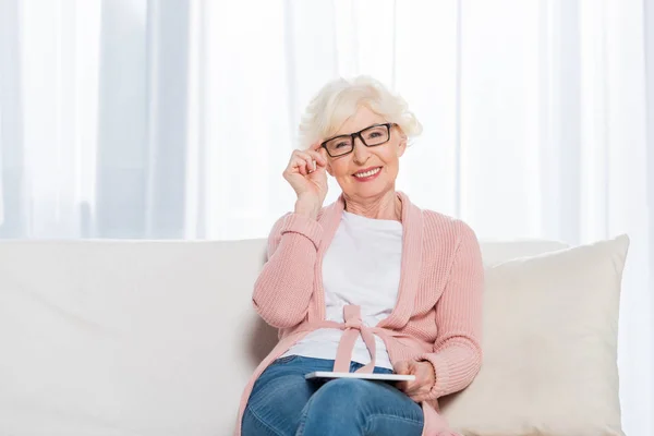 Portrait Smiling Senior Woman Eyeglasses Tablet Hands Resting Sofa Looking — Stock Photo, Image