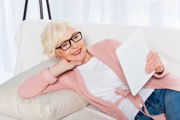 Retrato Mulher Idosa Sorridente Óculos Usando Tablet Enquanto Descansa Sofá — Fotografia de Stock