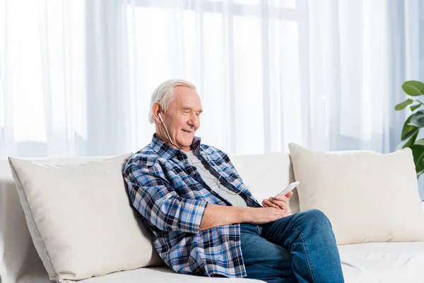 Side View Smiling Senior Man Earphones Smartphone Resting Sofa Home — Stock Photo, Image