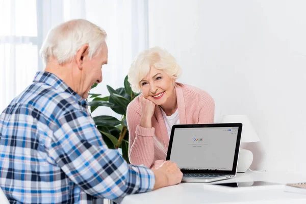 Retrato Mulher Idosa Alegre Olhando Para Marido Trabalhando Laptop Casa — Fotografia de Stock