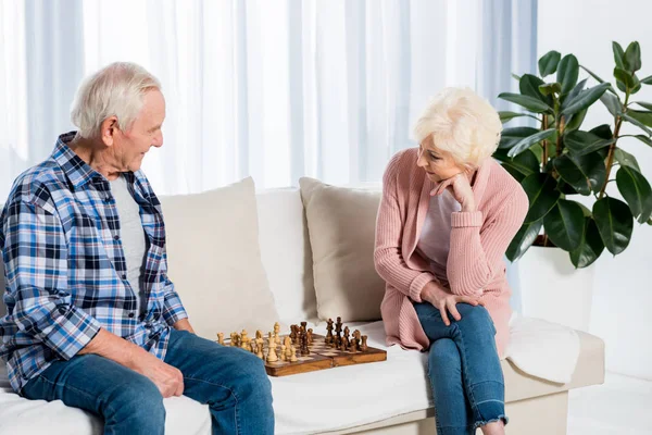 Концентрированная Старшая Пара Играет Шахматы Дома Диване — стоковое фото