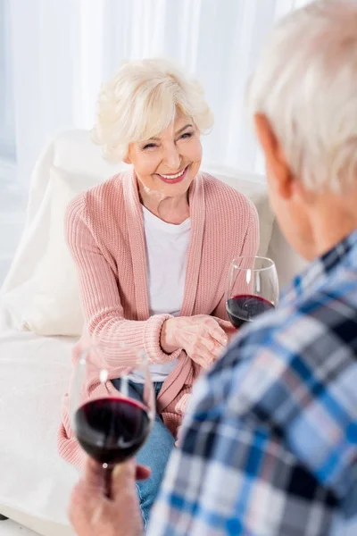 partial view of man giving glass of red wine to cheerful wife at home