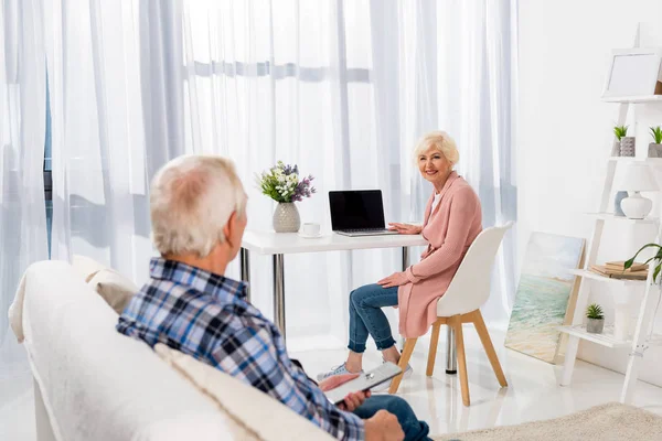 Lyckliga Senior Par Umgås Hemma Medan Kvinnan Använder Laptop — Stockfoto