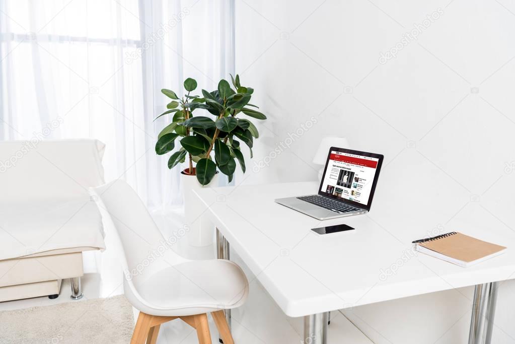 Home office with laptop with bbc logo, smartphone and notebook on table