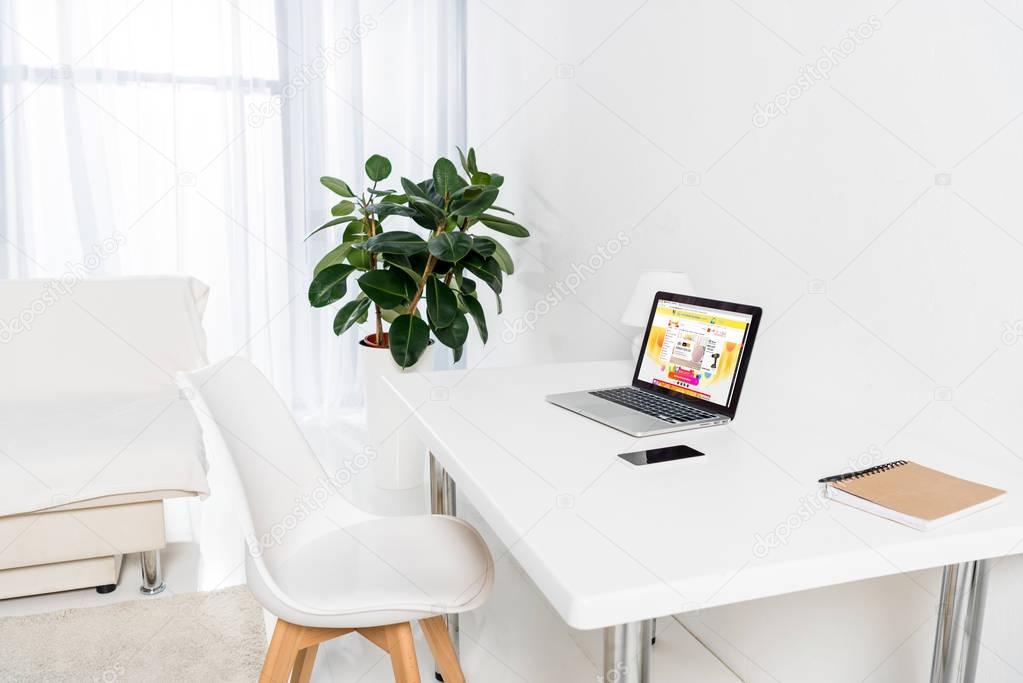 Home office with laptop with aliexpress logo, smartphone and notebook on table