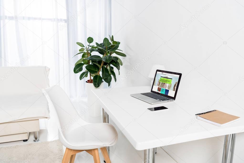 Home office with laptop with bbc logo, smartphone and notebook on table