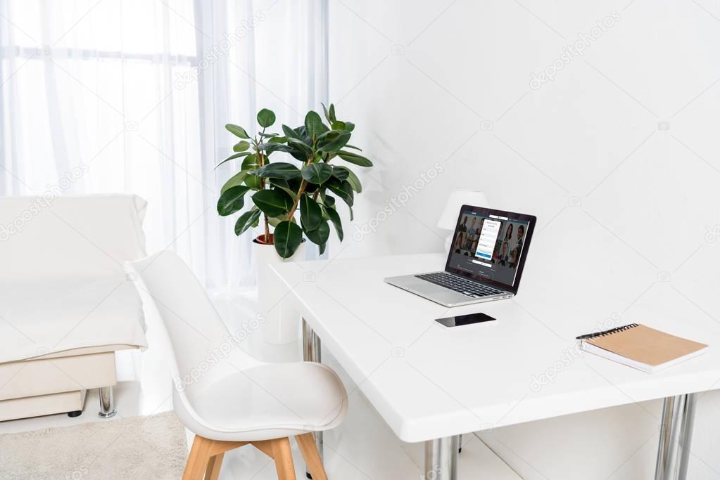 Laptop, smartphone and notebook on table in living room