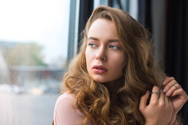 attractive girl with curly hair looking at the window