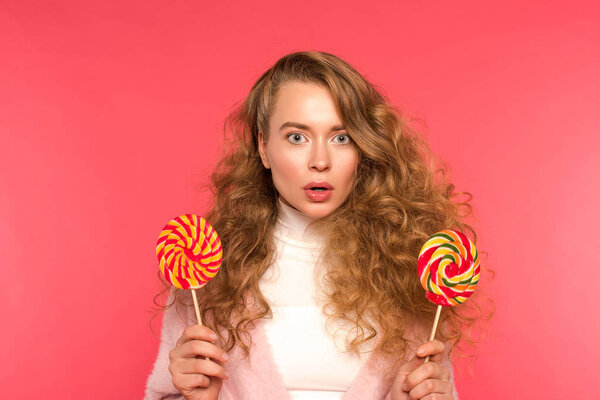 surprised girl holding two round lollipops isolated on red