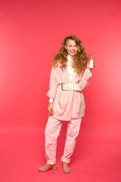 stylish girl in pink outfit holding milkshake isolated on red