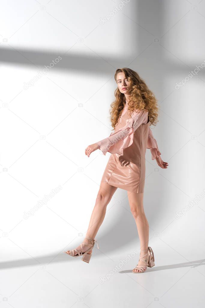 attractive woman in beige dress going and looking at camera
