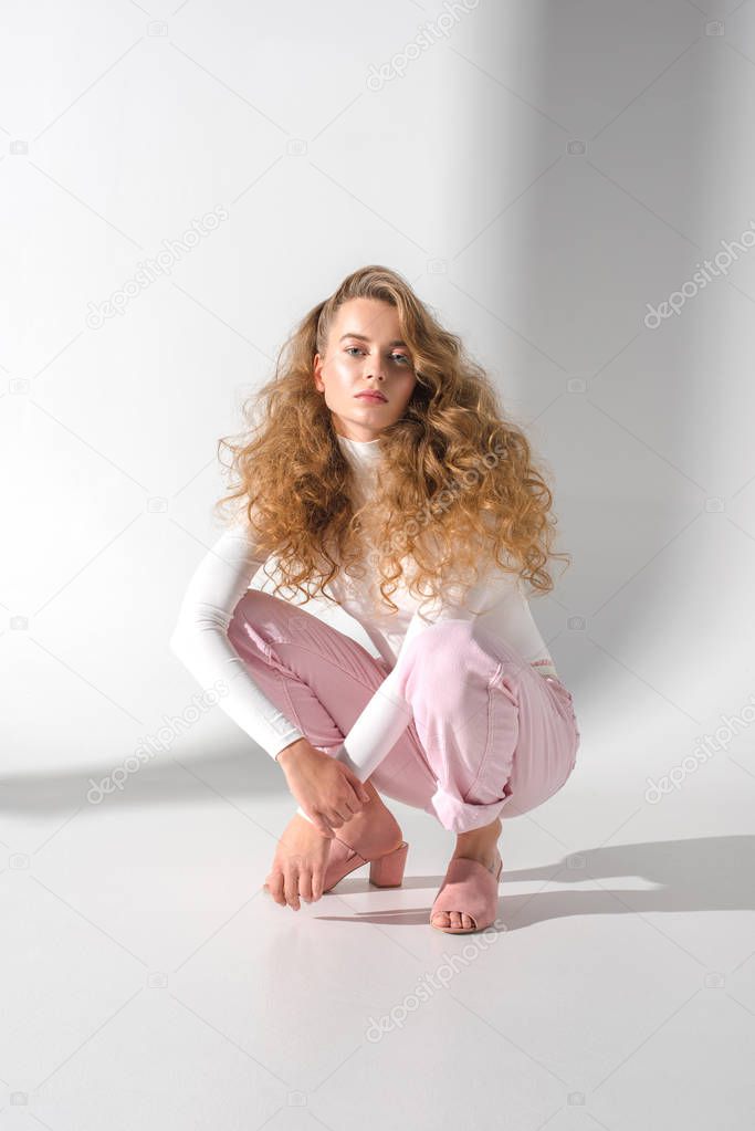 beautiful girl with curly hair squatting and looking at camera