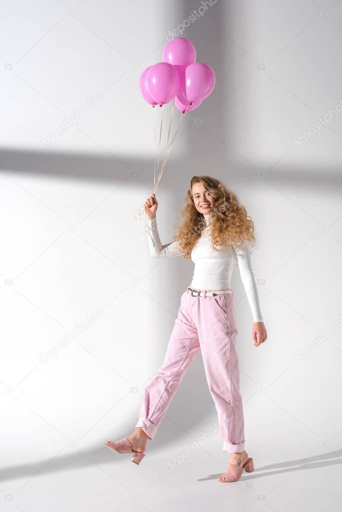 smiling woman going with bundle of pink balloons