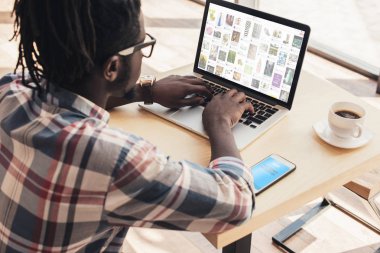 Afrika kökenli Amerikalı adam dizüstü pinterest Web sitesi ve smartphone ile skype cihaz ile kullanma