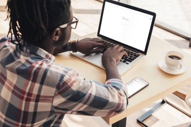 Afrika kökenli Amerikalı adam dizüstü cihaz ile google web sitesi ve smartphone ile kullanma
