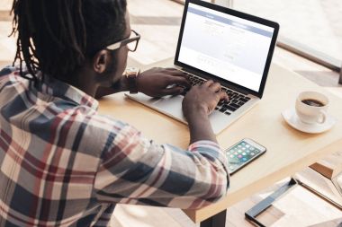 Web sitesi facebook ve kafede smartphone ile dizüstü bilgisayar kullanan Afrikalı-Amerikalı adam