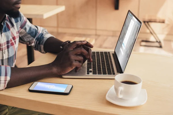 Przycięte Widok African American Człowieka Pomocą Smartfona Shazam Laptopa Linkedin — Zdjęcie stockowe