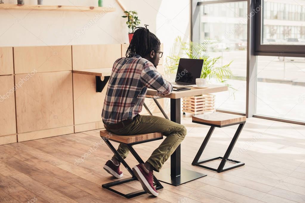 african american man using laptop in coffee shop