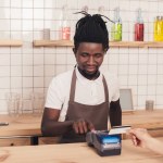 African american barista with credit card reader  at bar counter