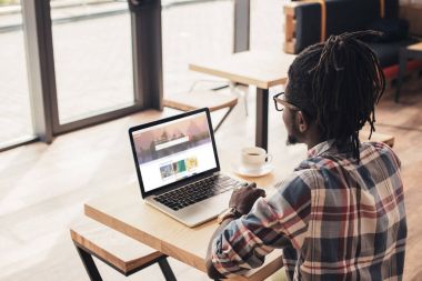 kafede shutterstock Web sitesi ile dizüstü bilgisayar kullanan Afrikalı-Amerikalı adam