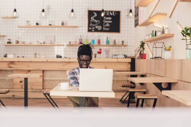 kafede dizüstü bilgisayar kullanan Afrikalı-Amerikalı adam