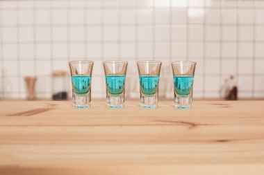 blue cocktails in shot glasses standing on bar counter clipart