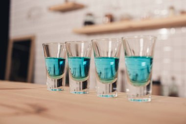 close up of blue cocktails in shot glasses standing on bar counter clipart