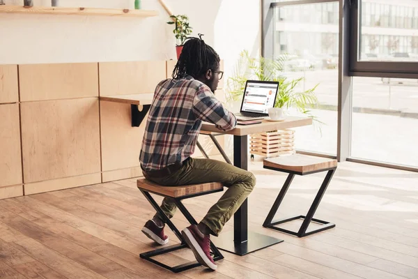 非洲裔美国人的背面视图使用笔记本电脑与 Soundcloud 网站在咖啡店 — 图库照片