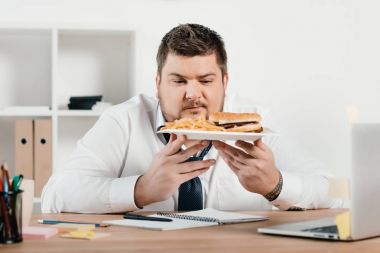 hamburger ve kızarmış patates Office ile kilolu iş adamı