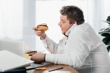 ofiste çalışırken hamburger yeme işadamı kilolu