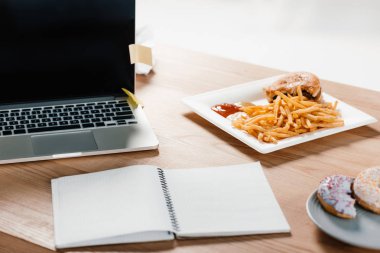 dizüstü bilgisayar, not defteri, çörek ve hamburger işyerinde patates kızartması ile 