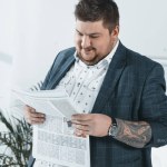 Empresário gordo em terno ler jornal no escritório