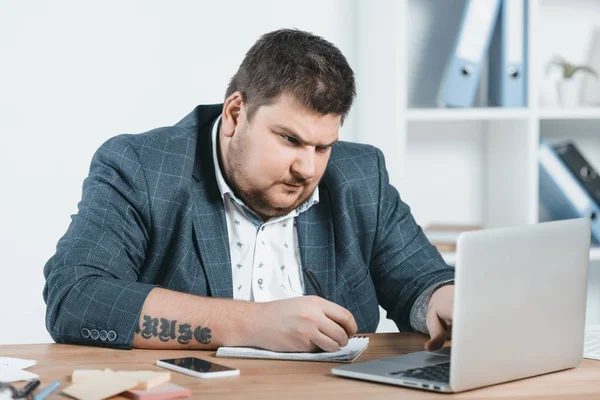 太りすぎのスーツを書くと職場でノート パソコンでの作業で実業団 — ストック写真